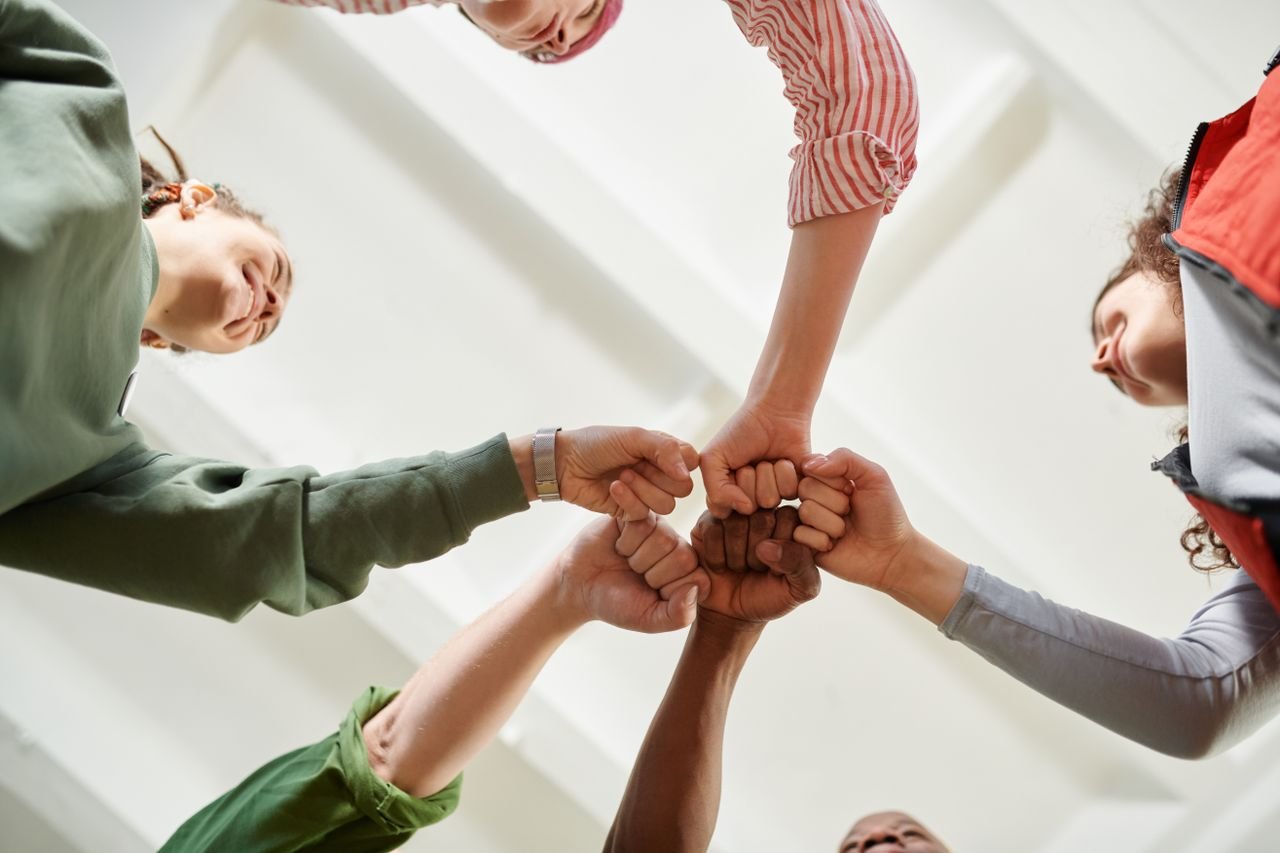 hero-services Four diverse team members join fists together, displaying unity and teamwork.